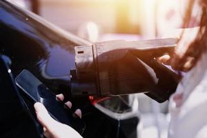 hand- aansluiten in een oplader in een elektrisch auto stopcontact.elektrisch auto of ev is opladen Bij station foto