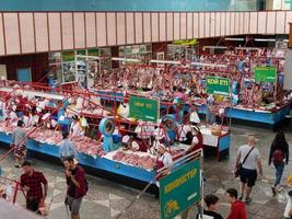 almatië, kazachstan, 2019 - mensen in de vlees sectie van de beroemd groen bazaar van almatië, kazachstan, met goederen Aan Scherm. foto