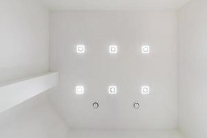 verlaagd plafond met halogeenspots lampen en gipsplaten constructie in lege ruimte in appartement of huis. spanplafond wit en complexe vorm. foto
