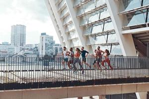 vol lengte van jong mensen in sport- kleding jogging terwijl oefenen Aan de brug buitenshuis foto