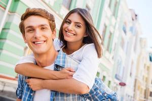 hebben pret samen. laag hoek visie van mooi jong liefhebbend paar staand buitenshuis samen terwijl vrouw knuffelen haar vriendje en glimlachen foto