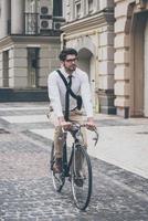 krijgen naar werk door fiets. zelfverzekerd jong Mens in bril op zoek weg terwijl rijden zijn fiets foto