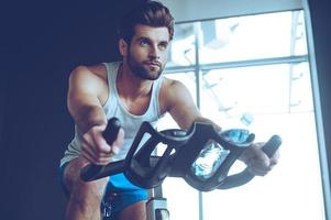 zelfverzekerd fietser. laag hoek visie van jong Mens in sportkleding wielersport Bij Sportschool foto