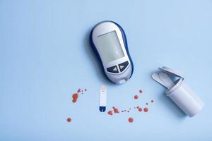 top wedijveren glucose meter en bloed druppels Aan een blauw achtergrond. diabetes test concept foto