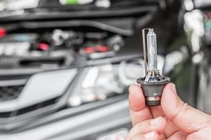 dichtbij omhoog auto koplampen xenon verlichting uitrusting in hand- een Mens met motor kamer voor onderhoud concept van auto foto