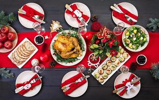 gebakken kalkoen. Kerstmis diner. de Kerstmis tafel is geserveerd met een kalkoen, versierd met helder klatergoud en kaarsen. gebakken kip, tafel. familie diner. top visie foto