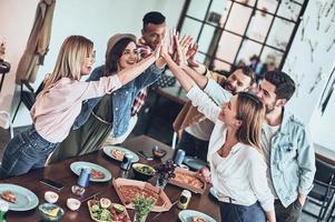 top visie van jong mensen in gewoontjes slijtage gebaren en glimlachen terwijl hebben een avondeten partij binnenshuis foto