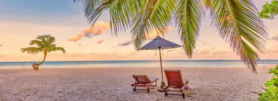 mooi tropisch zonsondergang landschap, romantisch stoelen, ligstoelen paraplu verbijsterend palm boom. wit zand, zee visie horizon, kleurrijk schemering lucht, rust en ontspanning. verbazingwekkend paar strand toevlucht foto