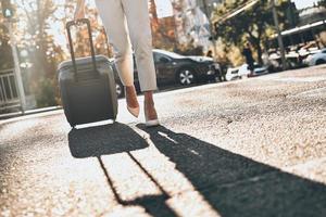 uitvoerend Aan de Gaan. dichtbij omhoog van jong vrouw trekken bagage terwijl wandelen buitenshuis foto