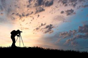 het silhouet van een professionele fotograaf is gericht op het fotograferen in een prachtige weide. foto