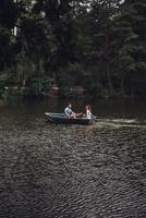 in liefde met natuur. mooi jong paar genieten van romantisch datum terwijl roeien een boot foto