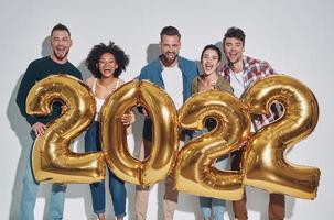 groep van jong mooi mensen in gewoontjes kleding draag- goud gekleurde getallen en glimlachen foto