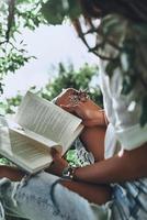 detailopname van jong vrouw Holding een Open boek terwijl uitgeven tijd buitenshuis foto