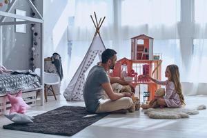 hij altijd begrijpt haar. vader en dochter spelen met een poppenhuis samen terwijl zittend Aan de verdieping in slaapkamer foto