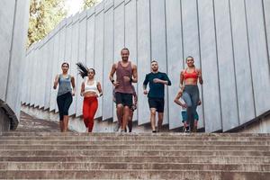 vol lengte van mensen in sport- kleding jogging terwijl oefenen Aan de stappen buitenshuis foto