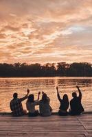 groep van jong mensen in gewoontjes slijtage glimlachen en nemen selfie terwijl genieten van strand partij in de buurt de meer foto