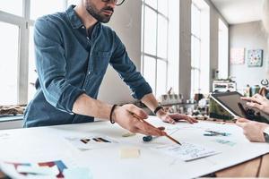 bespreken bedrijf. dichtbij omhoog van jong modern mensen in slim gewoontjes slijtage gebruik makend van blauwdruk terwijl werken in de creatief werken ruimte foto