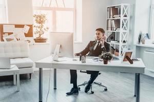 denken over nieuw oplossingen. knap jong Mens in formele kleding op zoek Bij computer toezicht houden op terwijl zittend Bij de kantoor bureau foto