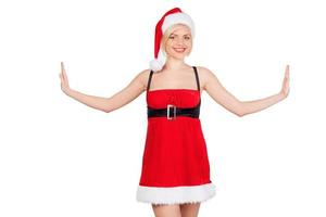 de kerstman meisje. mooi jong vrouw in de kerstman kostuum uitrekken uit haar handen en glimlachen terwijl staand geïsoleerd Aan wit foto