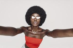 mooi jong Afrikaanse vrouw maken selfie terwijl staand tegen grijs achtergrond foto