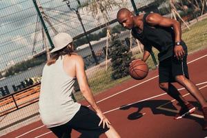 vastbesloten naar winnen. twee jong mannen in sport- kleding spelen basketbal terwijl uitgeven tijd buitenshuis foto