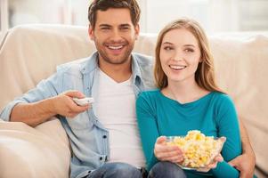 aan het kijken TV samen. mooi jong paar zittend Aan de bankstel samen en aan het kijken TV foto