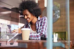 zakenvrouw op telefoon met behulp van digitale tablet in coffeeshop foto