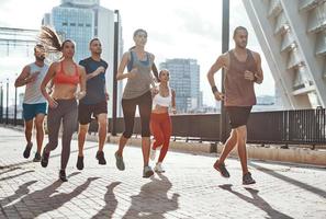 vol lengte van mensen in sport- kleding jogging terwijl oefenen Aan de trottoir buitenshuis foto