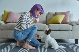 vrolijk jong vrouw voeden haar hond Bij huis foto