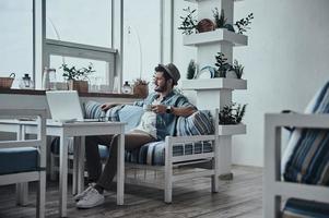 nemen sommige tijd naar denken. attent jong Mens Holding een kop en op zoek buiten terwijl zittend Aan de sofa foto