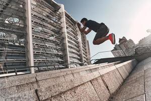 maken poging. jong Mens in sport- kleding jumping terwijl oefenen Aan de trap buitenshuis foto