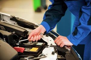 monteur Bij werk. detailopname van Mens in uniform repareren auto terwijl staand in werkplaats foto