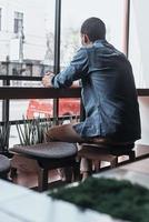 ontspannende in de cafe. achterzijde visie van Mens op zoek buiten terwijl zittend in de cafetaria foto