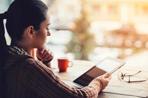 genieten van werk en vers lucht. kant visie van mooi jong vrouw Holding digitaal tablet terwijl zittend Bij de ruw houten tafel foto