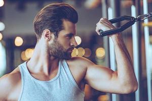 werken met biceps. dichtbij omhoog van jong Mens in sportkleding oefenen Bij Sportschool foto