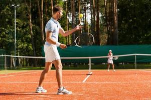 voorbereidingen treffen naar zijn het beste dienen. vol lengte van Mens en vrouw spelen tennis Aan tennis rechtbank foto