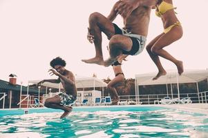 zwembad plezier. groep van mooi jong mensen op zoek gelukkig terwijl jumping in de zwemmen zwembad samen foto