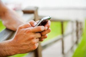 bericht naar een vriend. detailopname van Mens typen bericht Aan mobiel telefoon terwijl staand buitenshuis foto