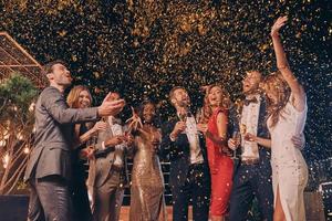 groep van mooi mensen in formele kleding hebben pret samen met confetti vliegend allemaal in de omgeving van foto