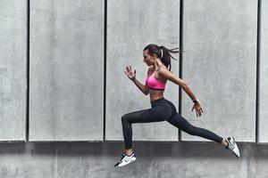 lang springen. modern jong vrouw in sport- kleding jumping terwijl oefenen buitenshuis foto