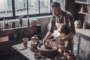 creëren iets Super goed samen. top visie van zelfverzekerd jong Mens en weinig jongen maken keramisch pot Aan de pottenbakkerij klasse foto