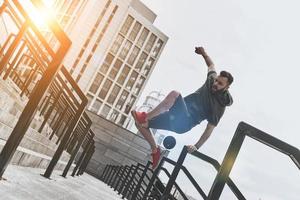 klaar naar overwinnen ieder obstakel. vol lengte van knap jong Mens in sport kleding jumping over- traliewerk terwijl oefenen buiten foto