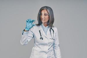 volwassen mooi vrouw dokter in gezicht schild Holding een fles met vaccin foto