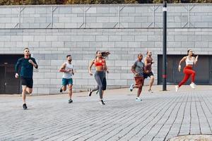 vol lengte van jong mensen in sport- kleding jogging terwijl oefenen buitenshuis foto