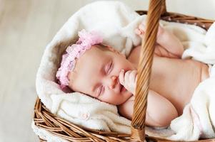 schattig baby in een slecht mand. top visie van weinig baby slapen terwijl aan het liegen in rieten mand en gedekt met handdoek foto