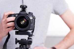 klaar naar schieten. detailopname van Mens Holding digitaal camera terwijl staand in studio met verlichting uitrusting Aan achtergrond foto