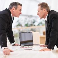 bedrijf confrontatie. twee volwassen mannen in formele kleding tegenstrijdig terwijl staand gezicht naar gezicht foto