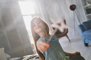 echt prinses. schattig weinig meisje spelen met een magie toverstaf terwijl uitgeven tijd Bij huis foto