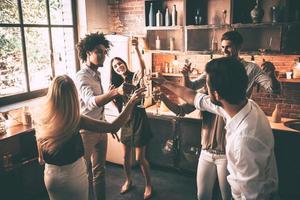 eindeloos feest. top visie van vrolijk jong mensen dansen en drinken terwijl genieten van huis partij Aan de keuken foto