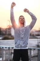 elke dag winnaar. opgewonden jong Mens houden armen verheven en uitdrukken positiviteit terwijl staand buitenshuis foto